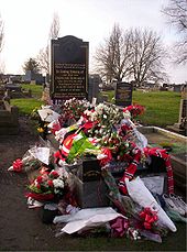 A gravestone almost entirely covered in floral tributes