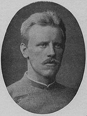  Head and shoulders of a young, fair-haired man with a blond moustache, looking to the right. He is wearing a jacket buttoned to the neck.