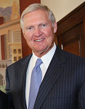 Head shot of an older white man wearing a black suit and blue tie