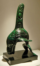 Jade carving of a killer whale with exaggerated fins and bared teeth. Its body and fins are engraved with nested ovals and other patterns.