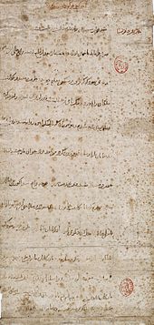 Long vertical mottled grey paper, with a dozen widely spaced lines of horizontal Arabic-looking script. There are two small oval red designs which have been stamped along the righthand margin of the paper.