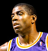 Head shot of a bald black man wearing a purple basketball jersey