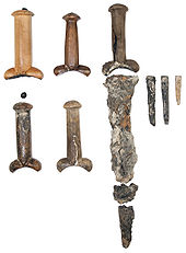 Five dagger handles with bulbous guards with the badly corroded remains of a few steel blades against a white background