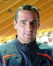 Roman Sebrie headshot with him wearing a black tracksuit top with red trim