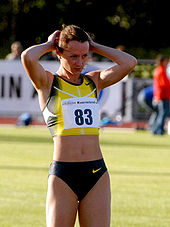 Yelena Slesarenko with her hands on her head, wearing a yellow and blue top and blue running briefs