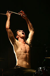 A shirtless man playing the drums