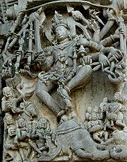Relief sculpture of deity with 10 arms and people below