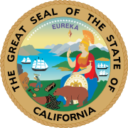 Circular seal surrounded by "THE GREAT SEAL OF THE STATE OF CALIFORNIA", with "EUREKA" atop the central image. A seated woman wearing ancient Roman warrior dress, with a shield at her feet, a spear in one hand, and a crested centurion's helmet, looks over a bay with four sailing ships. A small brown bear at her feet noses at vegetation. A miner in the near distance swings a pickaxe into the dirt near a shovel, pan, and sluice. Tall mountains line the bay, and 31 stars arc through the sky.