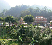 A temple in the middle of a forest with mountains in the background