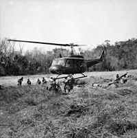 A black and white image of an Australian Iroquois helicopter inserting troops into a Landing Zone during the battle