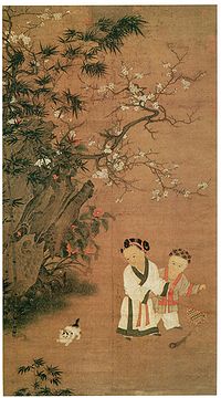 Two young girls play with a toy consisting of a long feather attached to a stick, while a cat watches them. There is a large rock formation and a flowering tree to the left of the girls and the cat.
