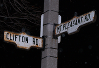 Two street signs on a cement pole at night