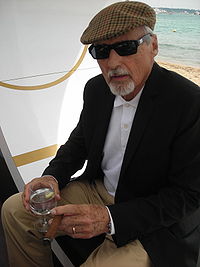 Dennis Hopper, with gray hair and a gray goatee, wearing a hat and sunglasses