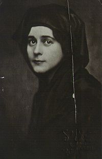 Black-and-white photographic portrait of a young white woman wearing a black Islamic veil.