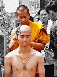 A Buddhist monk shaving the head of a devotee to prepare him for priesthood.