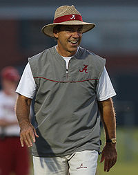 Coach Saban smiles at practice in a gray vest and hat.