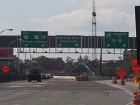 A split in a multilane freeway under construction with three green overhead signs. The left sign reads west Route 139 to U.S. Route 1 and 9 Interstate 280 Pulaski Skyway with two downward arrows, the middle sign reads Kennedy Boulevard Jersey City with two downward arrows, and the right sign reads New Jersey Turnpike Interstate 78 to Interstate 95 with two arrows pointing to the upper right.