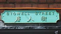 A street sign, painted green, bearing the name Stowell Street and three Chinese characters