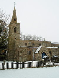 A stone church seen from the southwest with, from the left, a tower with a steeple, the nave with clerestory and porch, and to the right the chancel