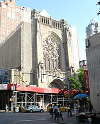 The church shown previously with the sidewalk covered and screens and scaffolding along either side.
