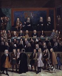 A large number of wigged, robed figures in a wood-covered courtroom. A large royal crest decorates the rear wall, with four judges sitting in front of it. Below them, a group of scribes sit writing, along with a large jewelled sceptre and cushion.
