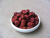 A bowl of reddish purple, oval shaped fruits with raisin texture.