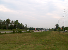 A rural highway with a wide right-of-way vanishes into the distance.