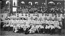 Two rows of men in white baseball uniforms. Those in the back row wear dark baseball caps with "P" on them while the men in the front row wear white hats and have "BOSTON" on the chest of their uniforms.