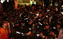 A tightly-bundled group of police officers in riot gear assembled in Jackson Road