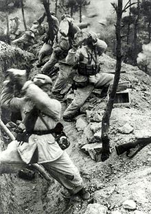 A line of soldiers are standing in front of a trench and holding rocks over their shoulders. Rocks are flying to the right while smokes are filling the background.