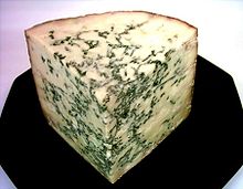 A corner of cheese with greenish streaks through it