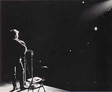 A spotlight shines on Dylan as he performs onstage.