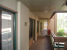 An outdoor hallway. Hotel rooms are on the left and a balcony is on the right.