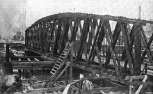 Black and white photograph showing a wooden railroad bridge