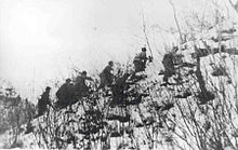 A group of soldiers climbing up a snow covered hill