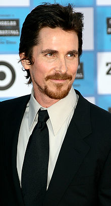 Christian Bale in a black suit at a movie premiere.