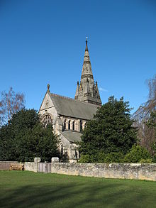 A stone church seen from the northeast with a large east window, a clerestory, and a tower with pinnacles and a spire