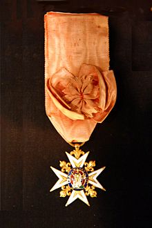 A neck-style military order: an elaborate cross with jewels and gold hangs from an orange ribbon