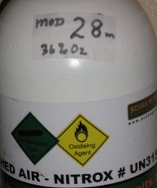 Closeup of a diving cylinder with a band reading "NITROX". A hand-printed label at the neck reads "MOD 28m 36% O2", with the 28 in much larger size.
