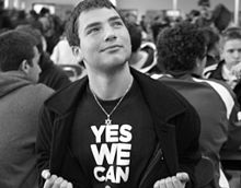 Daniel Jason Torres looking upward with a bemused expression on his face while wearing a T-shirt with a "Yes We Can" slogan