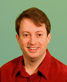 A man in a red shirt looks at the camera
