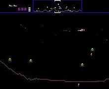 A horizontal rectangular video game screenshot that is a digital representation of a planet surface. A white, triangular space ship in the upper right corner battles green alien enemies. The top of the screen features a banner that displays icons, numbers, and a miniature version of the landscape.