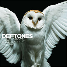 A snowy owl is shown with its wings open in front of a black background. On the complete left-side of the boarder, the words "Deftones" and "Diamond Eyes" are shown.