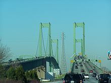 A congested divided freeway approaching a green twin-span bridge
