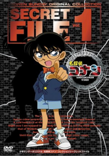 The DVD cover shows a young boy with black hair and glasses, wearing a blue vest with a white dress shirt showing underneath, light blue shorts, and a bow-tie. The boy is pointing his finger outside the cover accusingly. Above him in big red bold letters are the words Shonen Sunday Original Collection, Secret File Vol. 1. To the right of the boy is a bullet hole with the kanji for Meitantei Conan and under it in white letters are the words Shogakukan Video.