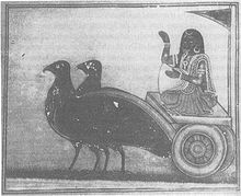 A grey-scale image depicting woman wearing a sari and gold ornaments sitting on a chariot pulled by two large black birds and holding a winnowing basket.