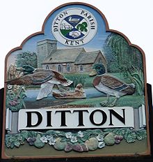 A photograph of an old church and ducks by a pond. The name of the village is shown above a row of flowers and fruit