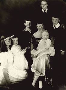 A mother surrounded by her six children of varying ages (two teenagers, two children, one toddler, one baby).