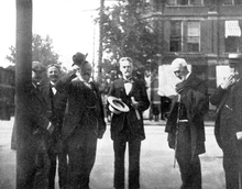 Black-and-white photograph of six men standing. All of them are well-dressed in suits and ties. Cope has short hair, mustache and a small beard; in his hands he holds a wide-brimmed hat and some papers.