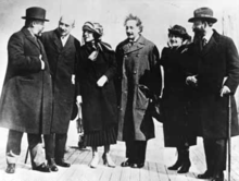 Casual group shot of four men and two women standing on a brick pavement.